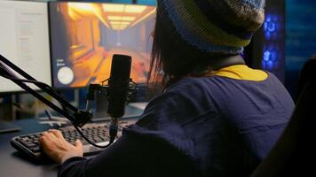 Back shot of pro gamer woman playing first person games using RGB keyboard in home studio. Gamer streaming gameplay using professional gaming equipment during online competition photo