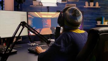 Back view of pro streamer playing game competition use professional setup with streaming chat open. Gamer sitting on gaming chair using professional headphones late at night in home studio photo