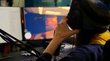 Close-up of streamer wearing professional gaming headphones and playing first person shooter games. Player sitting in streaming studio using technology network wireless during online competition photo