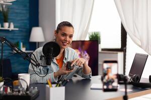 Social media presenter streaming computer mouse product review. Smartphone recording in home studio of woman vlogger presenting gadget recommendation for online social media channel. photo