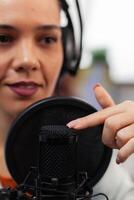 Closeup of influencer with headphones testing microphone sound. Woman content creator touching audio equipment with index finger. Sound check for online podcast streaming on social media. photo