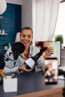 Content creator recording review of VR glasses with smartphone. Online podcast of smiling influencer presenting virtual reality goggles. Social media streaming for online recommendation chanel. photo