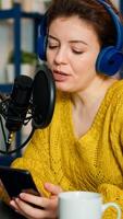 blogger reading questions from fans using smartphone during livestreaming from home podcast studio. Show production broadcast presenter streaming live content recording digital media photo