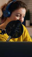 Happy blogger reading messages of fans using smartphone sitting in home podcast studio during livestreaming, recording. Online show On-air production internet broadcast host streaming live content photo