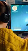 Pro gamer playing in the space shooter on personal computer. Woman gaming with teammates through headphones during online eSport tournament in action shot using technology network wireless photo