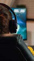 Back view shot of professional gamer playing in first-person shooter online game on computer. Virtual championship in cyberspace, esports player performing on pc during gaming tournament. photo