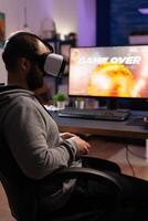 Man with vr glasses playing games with joystick on computer. Person losing game with virtual reality goggles and joystick in front of monitor. Player with online game. photo