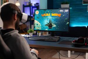 Player using vr glasses to win games on computer. Man with controller and virtual reality headset playing game to have fun with modern activity. Gamer winning online competition photo