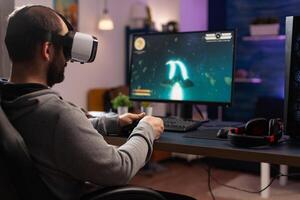 Adult playing games with vr glasses on computer, using gaming equipment. Man with virtual reality headset holding joystick to play online games. Player using controller for game photo