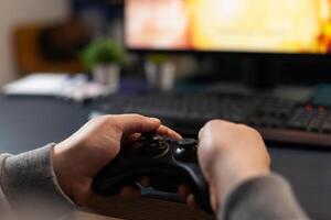 Close up of player holding joystick, losing games in front of computer. Gamer using joystick and playing online games on monitor, sitting at desk. Man gaming with modern equipment. photo