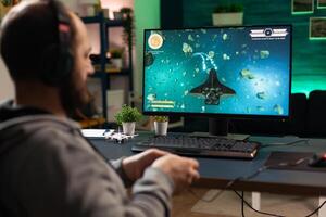 Gamer using headphones and joystick to play games on computer. Man playing with controller and audio headset for online gaming. Player having fun with equipment to play games. photo