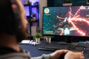 Close up of man using joystick to play online games on computer. Person playing game with joystick and headphones in front of monitor. Player having gaming equipment for fun. photo