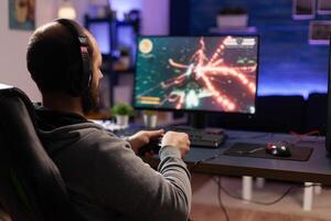 Person playing games with controller on computer. Player using joystick and wearing headphones to play online game on monitor. Modern man using gaming equipment to have fun. photo