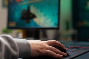Close up of player holding mouse with mousepad on desk to play games. Man using gaming equipment on computer, playing online game. Hand of player on gadget having fun with games photo