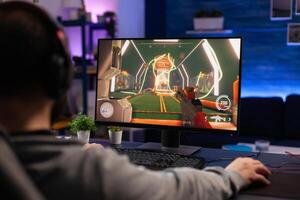 Man playing games on computer with mousepad and headphones. Gamer using mouse and headset to play online games on monitor. Player having fun with gaming equipment and electronic game photo