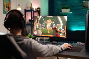 Adult playing games on monitor with mouse and headphones. Gamer using mousepad and headset to play online games on computer. Player having fun with gaming and electronic game photo