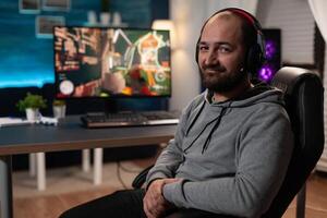 Portrait of streamer getting ready to play games on computer. Gamer with headphones preparing to stream live gameplay, playing with keyboard and mousepad on monitor. Player streaming photo