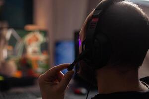 Close up of person streaming using microphone on headphones with computer. Man live streaming games play on monitor, talking to audience and playing online games for social media. photo