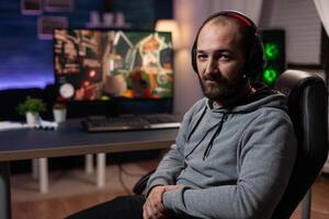 Portrait of man preparing to play games on computer. Gamer with headphones getting ready to stream live gameplay, playing with keyboard and mousepad on monitor. Player streaming photo