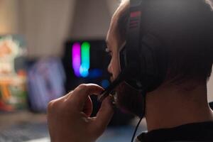 Close up of man using microphone on headphones to stream with computer. Gamer live streaming games play on monitor, talking to audience and playing online games for social media. photo