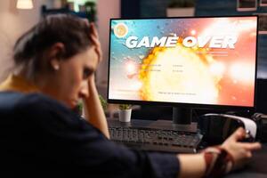 Frustrated woman losing online games on computer. Disappointed person playing on monitor, using controller and feeling sad about lost game. Gamer with electronic e sport. photo