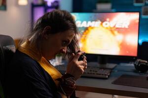 Frustrated gamer playing online games with controller. Woman using joystick on computer to play internet games and losing. Disappointed person with electronic gaming equipment. photo