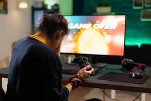 Angry woman playing online games with joystick. Gamer using controller on computer to play internet games and losing. Disappointed person with electronic gaming equipment. photo