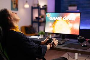 Disappointed adult losing online games on computer. Frustrated woman playing on monitor, using modern controller and feeling sad about lost game. Gamer with electronic e sport. photo
