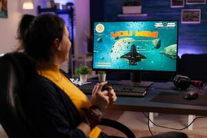 Gamer using controller to play games on computer. Happy woman winning online games with joystick in front of monitor. Person feeling cheerful and celebrating win on internet. photo