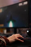 Close up of hands using mouse to play games on computer. Gamer playing digital game with mouse and pad in front of monitor to have fun. Player using online gaming equipment photo