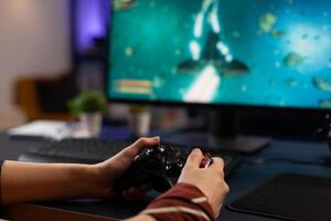 Close up of person using joystick to play games on monitor. Woman holding controller and playing digital games on computer. Person with gaming equipment to play online game. photo