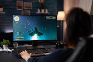 Gamer using keyboard to play digital games. Woman playing online game with control console on computer, doing fun activity. Player using modern gaming equipment in cyberspace. photo