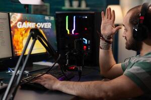 Player losing games on online stream with live chat. Man streaming gameplay on computer with headset and microphone. Streamer with headphones broadcasting games on social media. photo