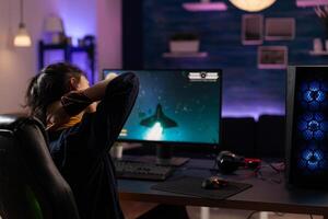 Person preparing to play games on monitor. Woman using keyboard and mousepad, playing online game on computer at desk. Player gaming in cyberspace, having fun with games. photo