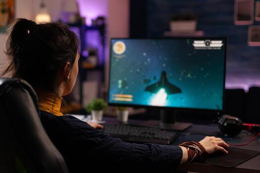 Adult using keyboard and mousepad to play games on computer. Gamer playing online game in front of monitor with control console and mouse on desk. Modern player with gaming equipment photo