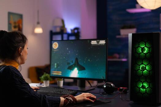 Woman playing games with keyboard and mouse on computer. Person using control console and mousepad to play digital games on monitor. Adult with electronic gaming equipment. photo