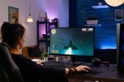 Person using keyboard and mouse to play games on computer. Gamer playing online game in front of monitor with control console and mousepad on desk. Modern player with gaming equipment photo