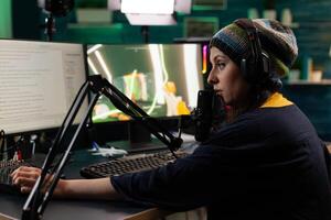 Woman streaming gameplay on computer with live chat. Person playing games on online stream, using microphone, headphones and modern equipment to play. Streamer gaming at desk photo