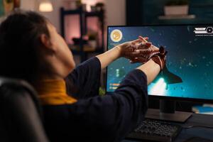 Gamer preparing to play online games on computer. Woman using keyboard and mousepad, playing digital game on monitor at desk. Player gaming in cyberspace, having fun with games. photo