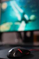 Close up of mouse in front of computer on desk. Mousepad and gaming equipment used to play games online on monitor. Game on digital cyberpace with modern gadgets on table. photo