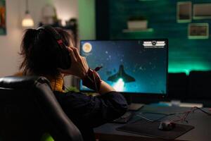 Woman using headphones to stream games play on computer. Gamer live streaming gameplay with headset and monitor. Player broadcasting game in cyberspace with modern equipment. photo