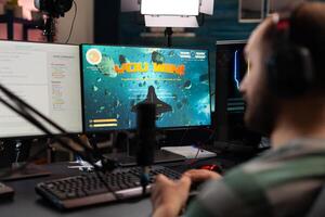 Streamer playing games with controller on computer. Man live streaming gameplay and winning, using microphone and headphones while he talks to online chat on monitor. Gamer on stream photo