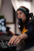 Close up of adult using streaming equipment on desk with headphones and microphone. Gamer talking to audience on broadcast, live streaming on computer. Streamer with electronic gadget photo