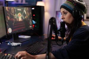 Woman using games play to stream online on computer. Streamer broadcasting gameplay live with chat on monitor, using headphones and microphone. Player streaming and gaming. photo