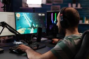 Person streaming games online with live chat. Player using headphones and microphone on computer, to play gameplay on live stream. Man broadcasting game with equipment at desk. photo