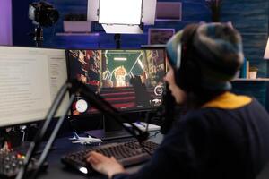 Woman live streaming games on monitor with chat. Person showing gameplay on online stream, using microphone, headphones and modern equipment to play. Streamer gaming live at desk photo