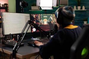 Player doing online live streaming with games. Woman using gameplay on computer to stream and looking at monitor with chat. Person broadcasting and playing games with microphone. photo
