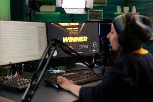 Person live streaming games on monitor. Woman broadcasting gameplay, playing online on stream with live chat, using monitor and microphone. Streamer wearing headphones to play. photo