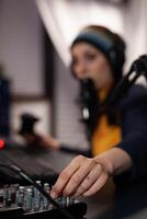 Close up of woman using streaming equipment live with headphones and microphone. Gamer talking to audience on online broadcast, live streaming on computer. Streamer with electronic gadget photo