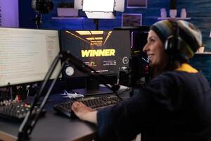 Player winning games on live stream with chat. Woman streaming gameplay online on computer with hmicrophone and headphones. Person broadcasting while she plays game. photo